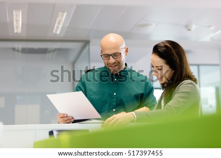 Businessman and businesswoman with paperwork in office
