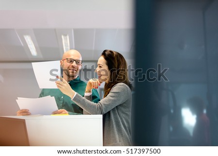 Businessman and businesswoman discussing over documents in office