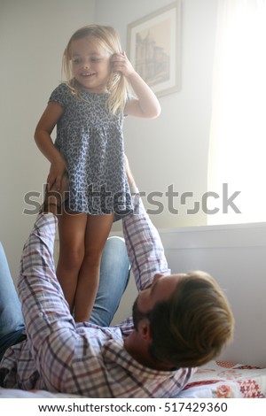 Father playing wit his daughter on the bed.