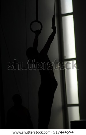 Silhouette down syndrome male athlete gym performance at the rings.