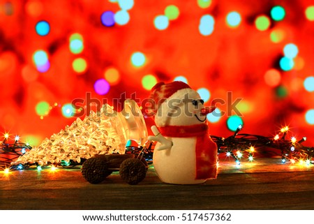 Dark evening Christmas and New Year`s card or poster with Snowman drags a truck glass tree on colorful bokeh background. Big copyspace place for text, logo, sale price and item description.