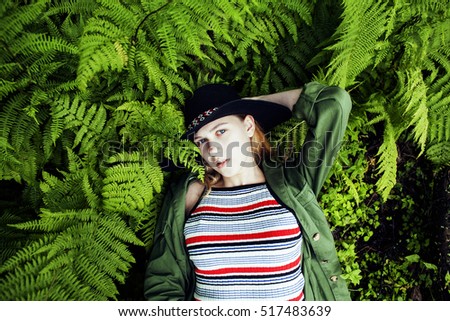 Pretty young blond girl hipster in hat among fern, vacation in g