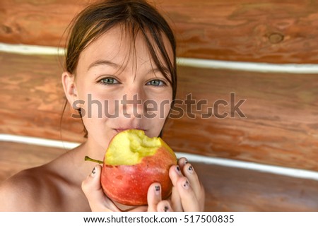 girl eating an apple at the cottage in summer Royalty-Free Stock Photo #517500835