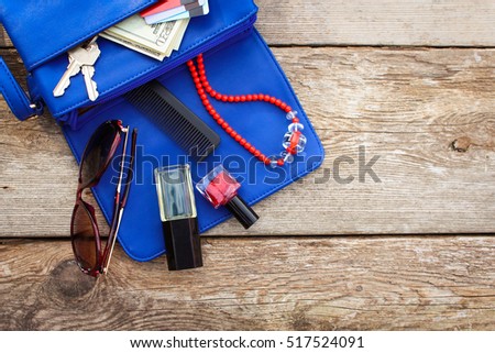 Things from open lady purse. Cosmetics, money and women's accessories fell out of blue handbag. Top view. 