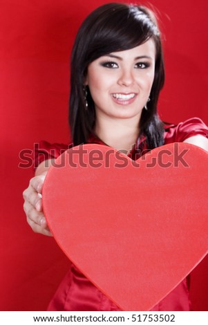 Stock image of woman holding heart shape over red background, selective focus on heart.