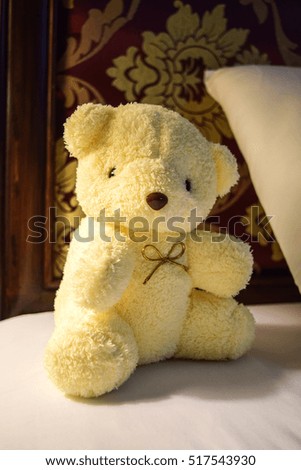 A bear doll sitting on the bed.