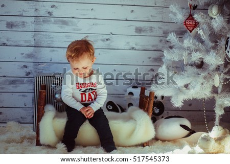 The small boy sits near christmas tree