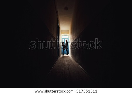 young man and woman standing in a dark corridor