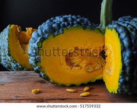 Organic green pumpkin and seed on wooden table with dark background.
