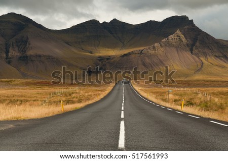 Road leads to a magnificent volcano mountain in the distance, in a dramatic scene in the Snaefellsjokull national park, Iceland.