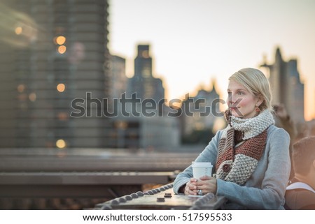 Beautiful Woman on the Brooklyn Bridge Looking at Manhattan with a Coffee during Sunset