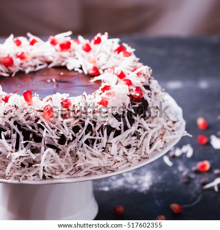 homemade sponge cake with chocolate icing decorated with pomegranate and coconut. selective focus