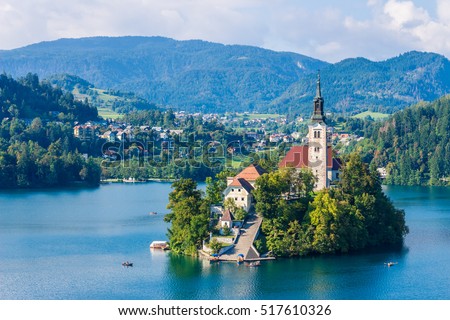 Lake Bled with St. Marys Church of Assumption on small island. Bled, Slovenia, Europe. Mountains and valley on background. Areal view from above. Staircase, stairs lead to church. Space for your text. Royalty-Free Stock Photo #517610326