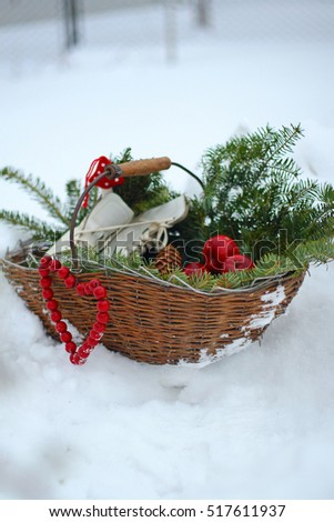 red apples, pine cones, vintage skates in wicker basket on snow background. cozy farmhouse rustic nordic scandinavian country cottage style decor. winter still life. christmas concept, card