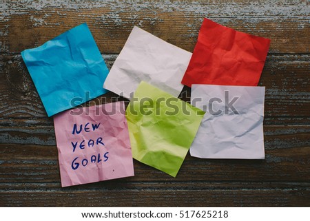 new year goals on colorful paper with clothespin hanging on a string with wooden background, retro style