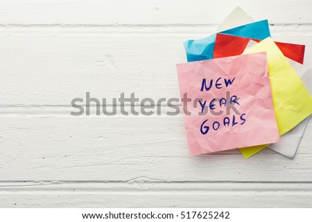 new year goals on colorful paper with clothespin hanging on a string with wooden background, retro style