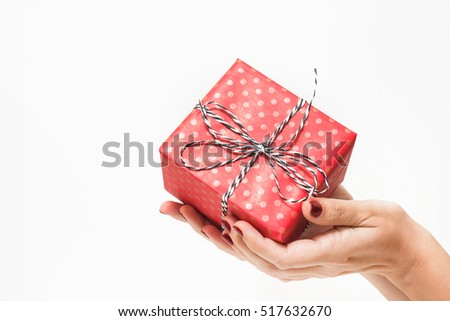 Young woman with beautiful red manicure holding small present in hands. Close up of box in wrapping paper isolated on white background. Horizontal color photo.