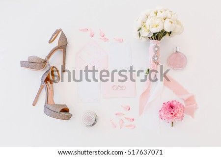 Wedding composition of shoes, bouquet with flowers, invitation letters, rings, perfume in pink colors