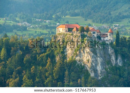Famous medieval castle on rock top, Bled, Slovenia. Castle built on a cliff for overlooking lake Bled. Filled full frame. View from aside. Close up. Beautiful sunset picture with castle and red roofs.