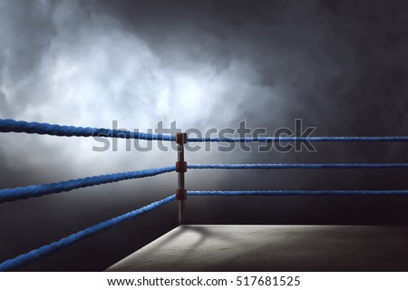 View of a regular boxing ring surrounded by blue ropes spotlit by a spotlight Royalty-Free Stock Photo #517681525