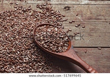 Flax seeds on a rough wooden background and a spoon. Healthy products, a source of vitamins and essential fatty acids, the raw material for oil. Still life photo.