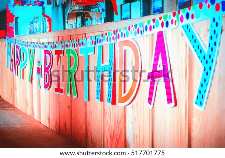 Motley Happy Birthday banner hanging on a wooden background. Selective focus.