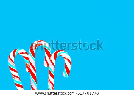 Striped red and turquoise lollipops candy canes on a blue backdrop. Greeting card, holiday background with space for copy.