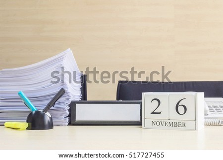 Closeup white wooden calendar with black 26 november word on blurred brown wood desk and wood wall textured background in office room view with copy space , selective focus at the calendar