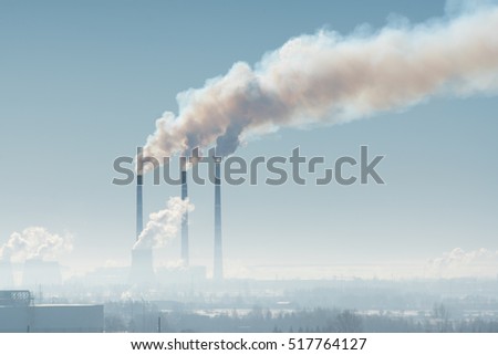Three industrial chimney with smoke against the gray sky Royalty-Free Stock Photo #517764127