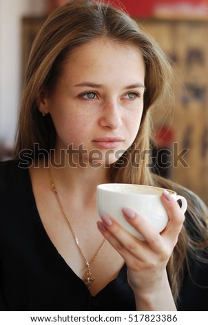 
a beautiful young girl drinking coffee in a coffee house