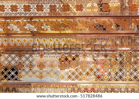 abstract background texture of golden orange  Buddhist temple's wall in Thailand which  presents surface of beautiful decorative reflection with linear pattern in dazzling dizzy smooth shady layer   
