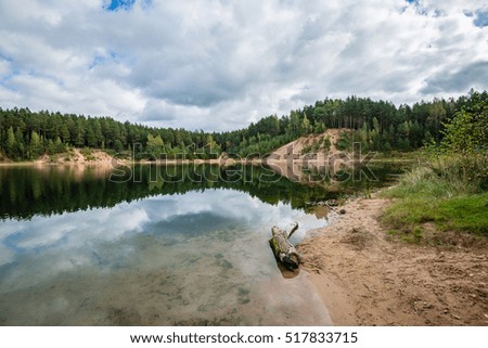 calm lake with reflections of clouds in summer with forest in background