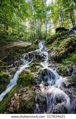 rocky waterfall in summer with stream and low water in forest