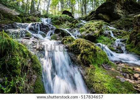 rocky waterfall in summer with stream and low water in forest