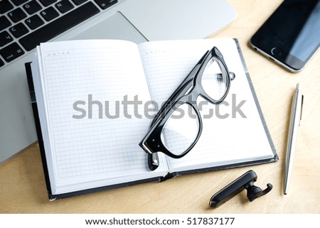 blank notebook, pen, glasses and laptop on the table