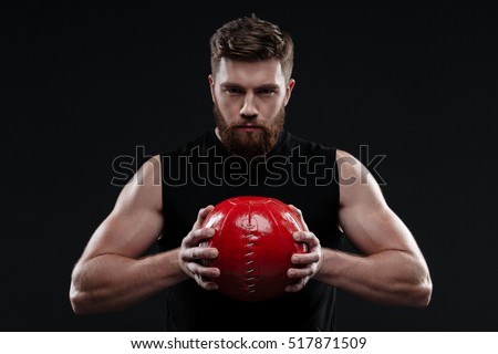 Serious trainer with ball. holding ball in hands. isolated dark background