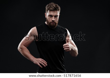 Cool athletic man in studio. shows finger up. isolated dark background