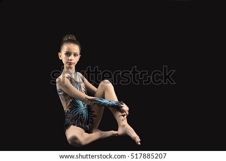 Young professional gymnast girl beauty practicing gymnastic isolated on black background
