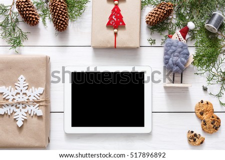 Christmas online shopping background. Tablet screen with copy space top view on white wood, present boxes and cookies. Electronic devices, internet commerce on winter holidays concept