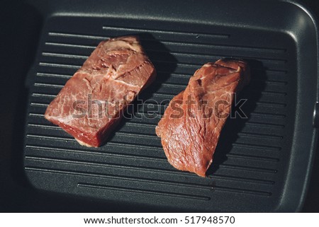 Raw uncooked beef beef steaks on grill pan background. Top view with filter and grain for vintage film effect