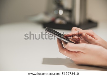 Close up of smartphone in hand. Close up of a woman hand holding a smartphone and texting. womans hands typing on smartphone over wooden brown table