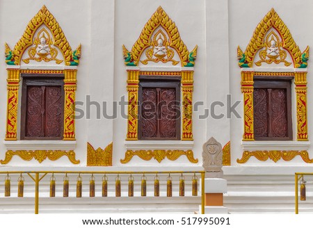 divine background texture of holy brownish wooden closing window surrounded by colorful stencil and Hindu gods above each frames located on whitish wall in a temple in Nakhon Panom, Thailand.