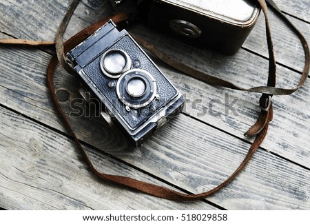 Old retro film camera and belt bag (leather case) on vintage wooden boards. 