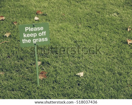 Vintage looking Please keep off the grass sign in a meadow