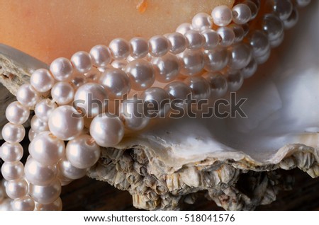 A close up view of a string of pearls on an oyster shell with a bar of homemade oatmeal soap.