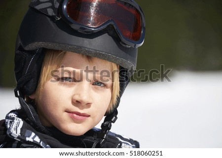 Portrait of little child boy in helmet and ski goggles on a sunny day in the mountains.