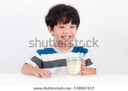 Happy Asian boy with a glass of milk, Isolated over white background. Royalty-Free Stock Photo #518067613