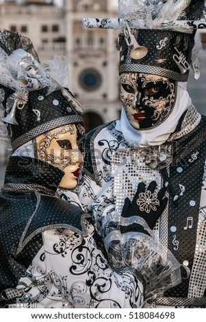 Beautiful couple of white, black and gold masks at St. Mark square during the carnival of Venice.