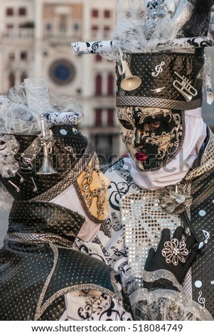 Beautiful couple of white, black and gold masks at St. Mark square during the carnival of Venice.
