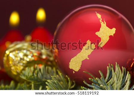 A glossy red bauble with the golden shape of New Zealand.(series)